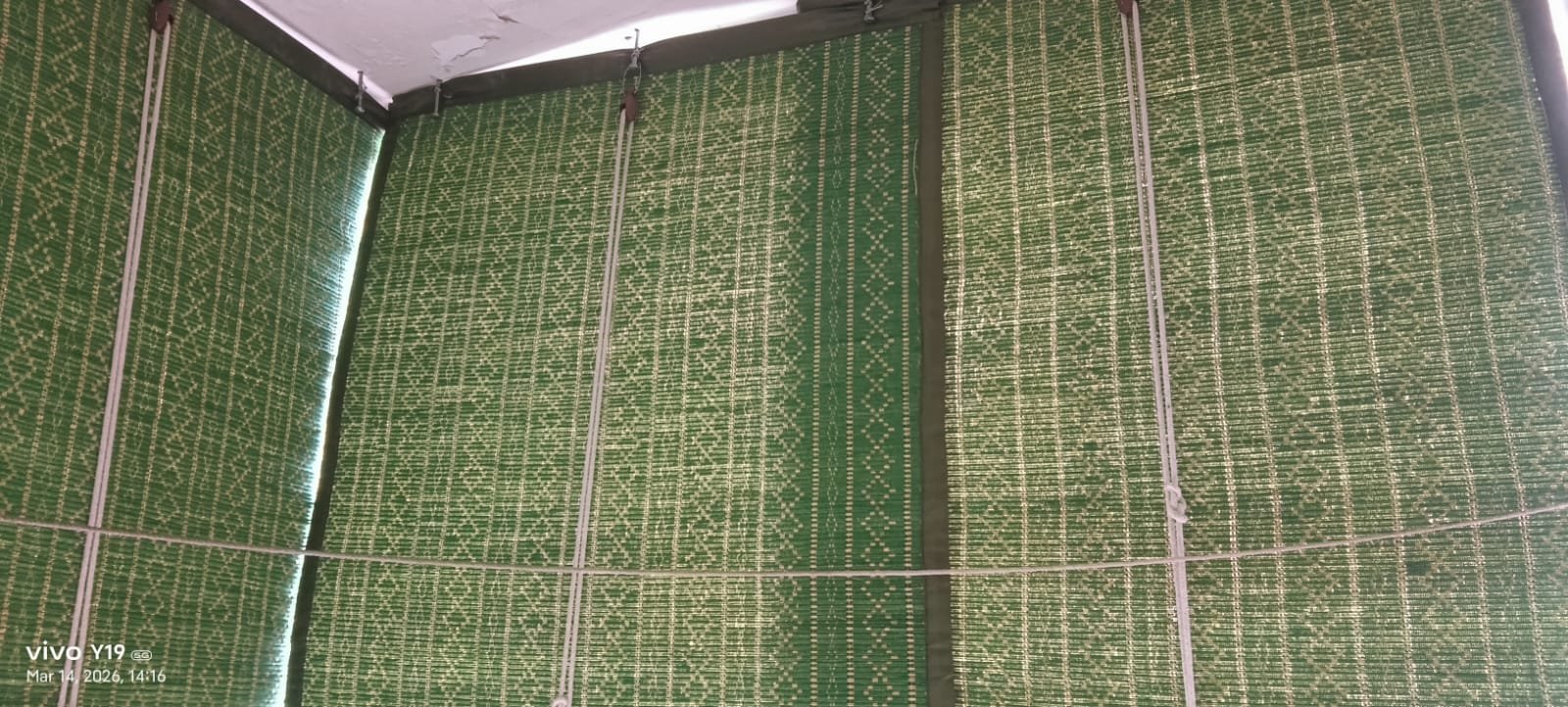 Decorative green patterned woven bamboo chick installed on balcony corner