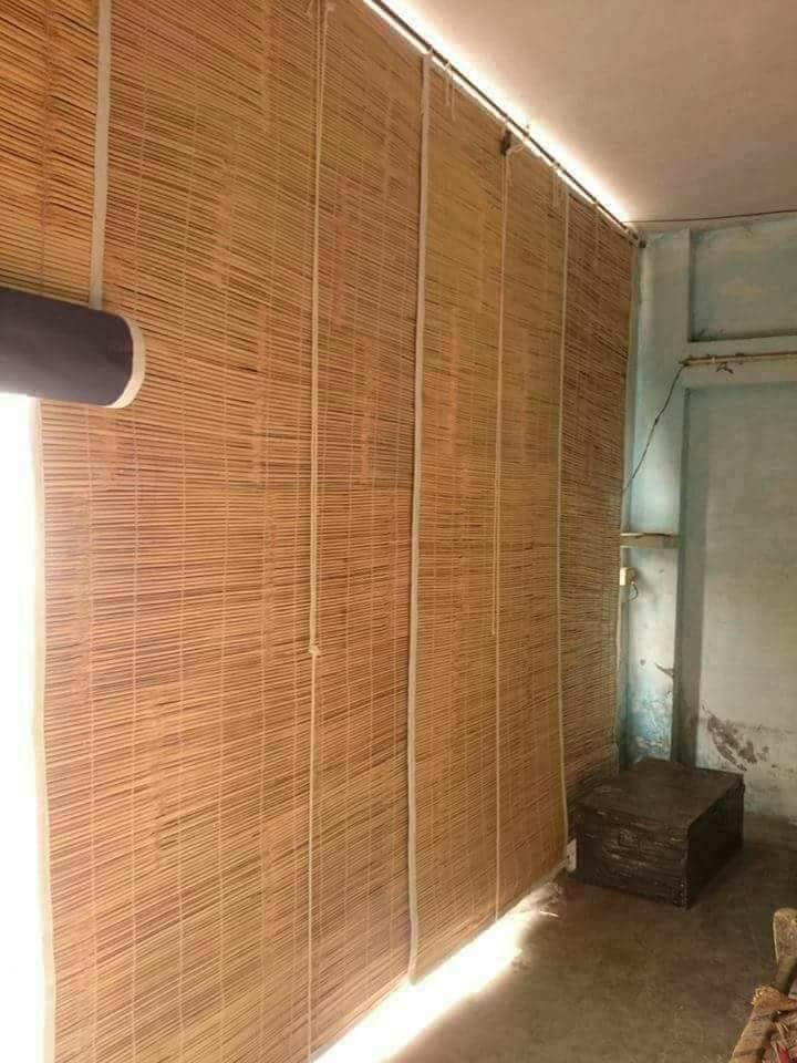 Vertical roll-up natural bamboo chick blind installed across sunlit balcony window